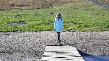秋天，穿着蓝色外套的年轻女子在湖上过桥